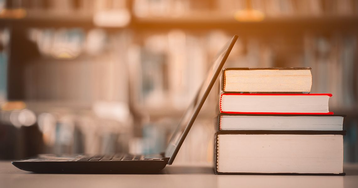 Laptop open and leaning against a stack of books