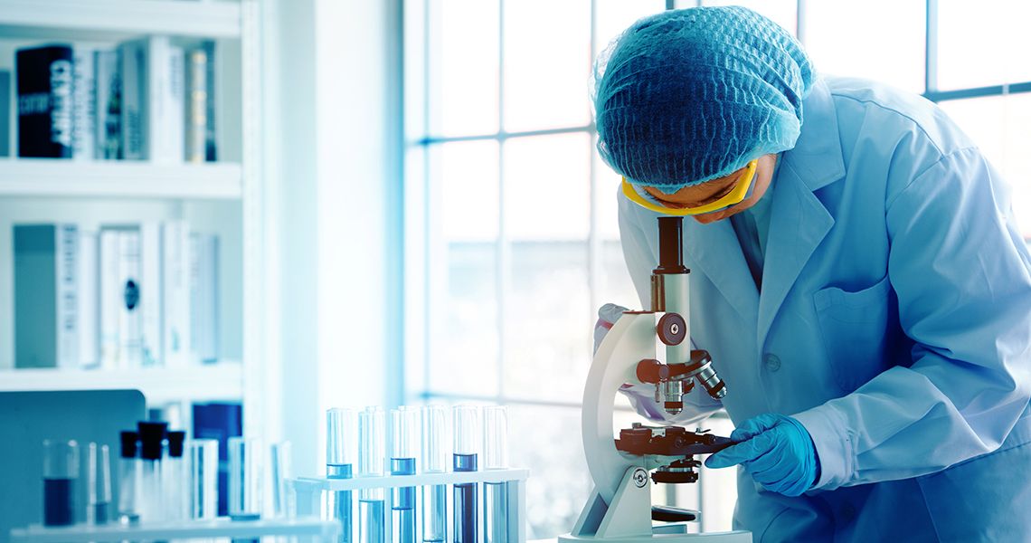 Scientist in a lab looking through a microscope