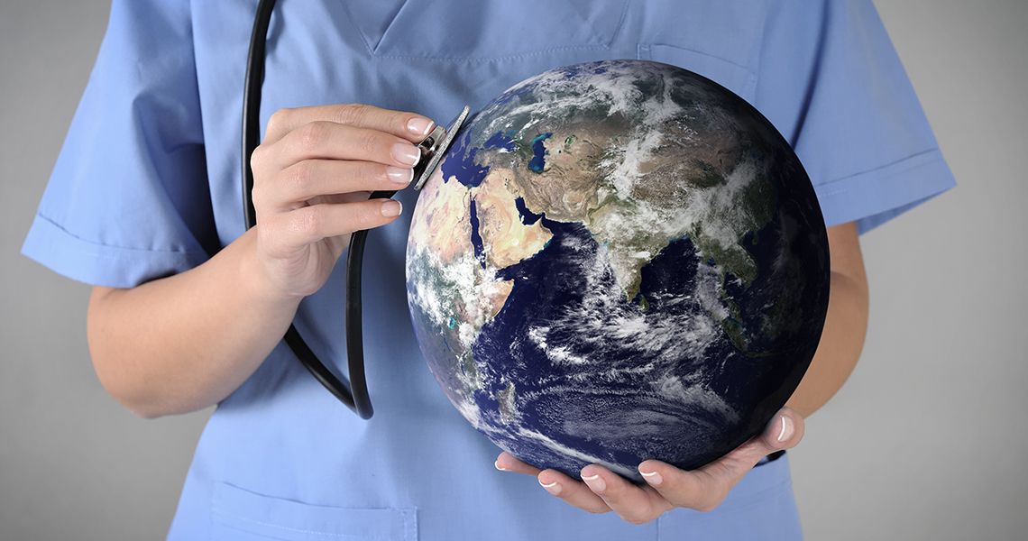 Doctor holding a stethoscope up to a globe