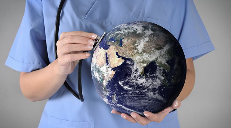 Doctor holding a stethoscope up to a globe